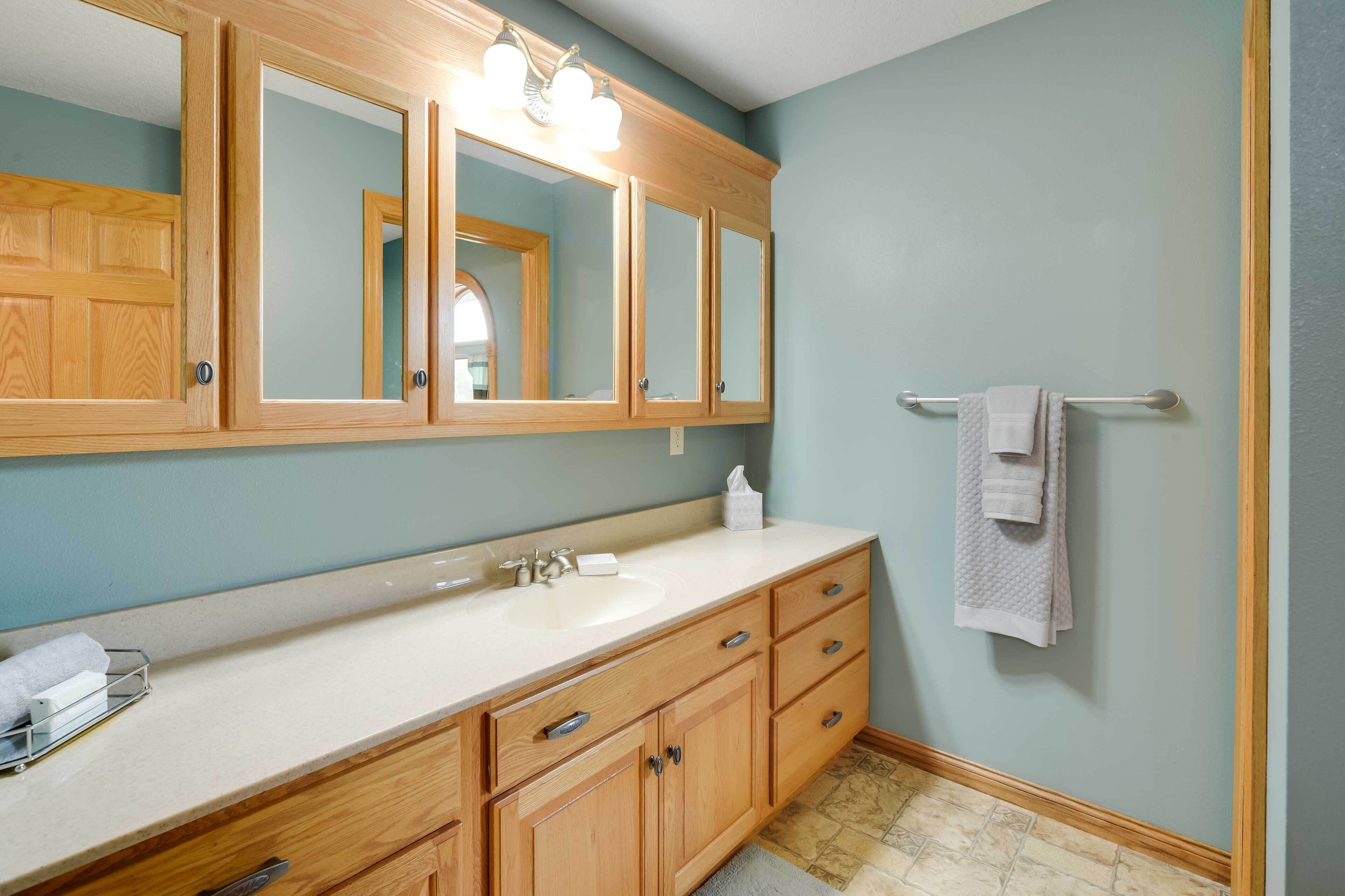 A bathroom with a wooden vanity, a large mirror, and a towel rack.