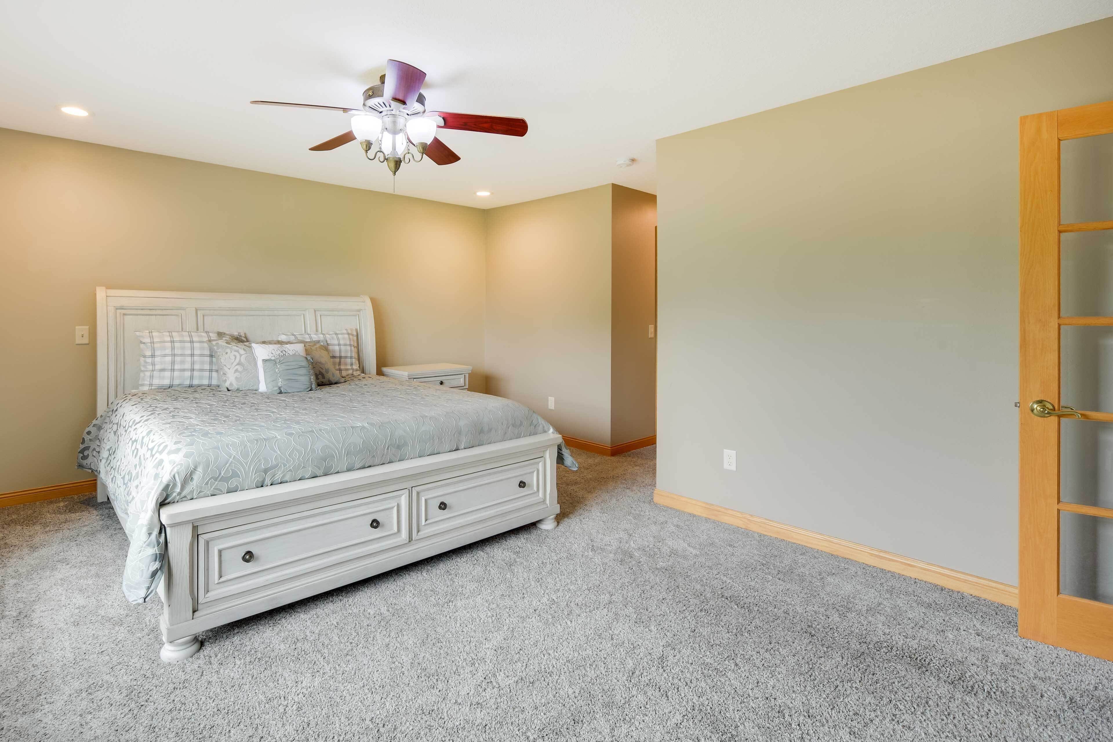 Un dormitorio con cama, ventilador de techo y puerta.