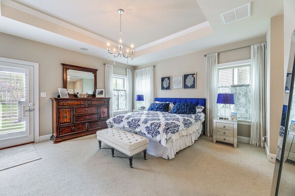 A bedroom with a large bed, a dresser, a bench, and a desk.