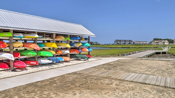 A covered boat storage area with multiple colorful kayaks and a wooden deck leading to a water body. - Furnished Outdoor Space: Family Home in Ocean View (Ocean View)