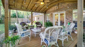 A covered patio area with wicker furniture, a ceiling fan, and a brick wall. - Charming Diamondhead Home w/ Private Yard! (Diamondhead)