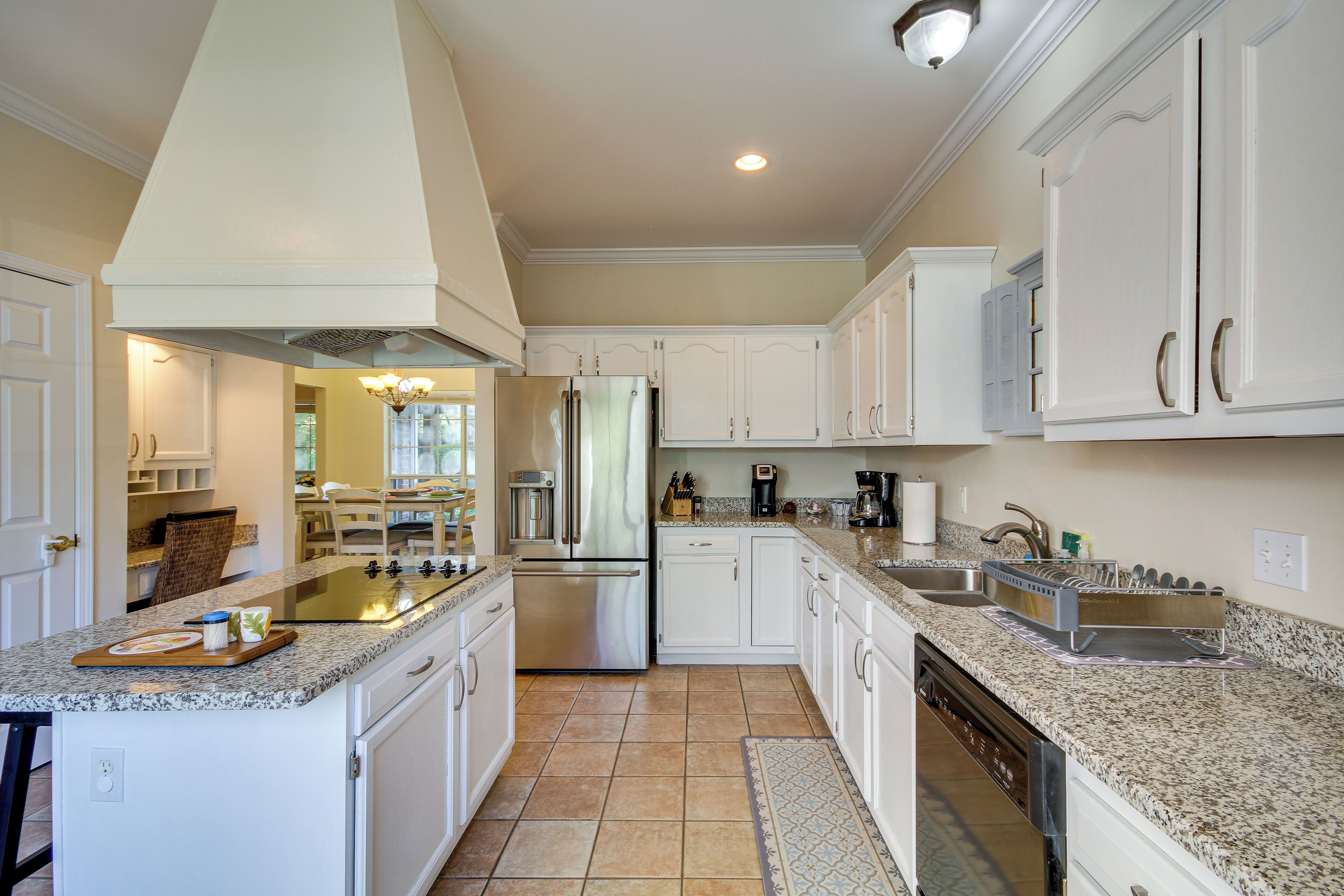 A modern kitchen with white cabinetry, stainless steel appliances, and granite countertops.