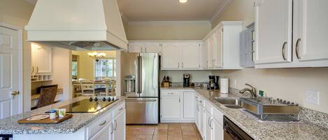 A modern kitchen with white cabinetry, stainless steel appliances, and granite countertops.