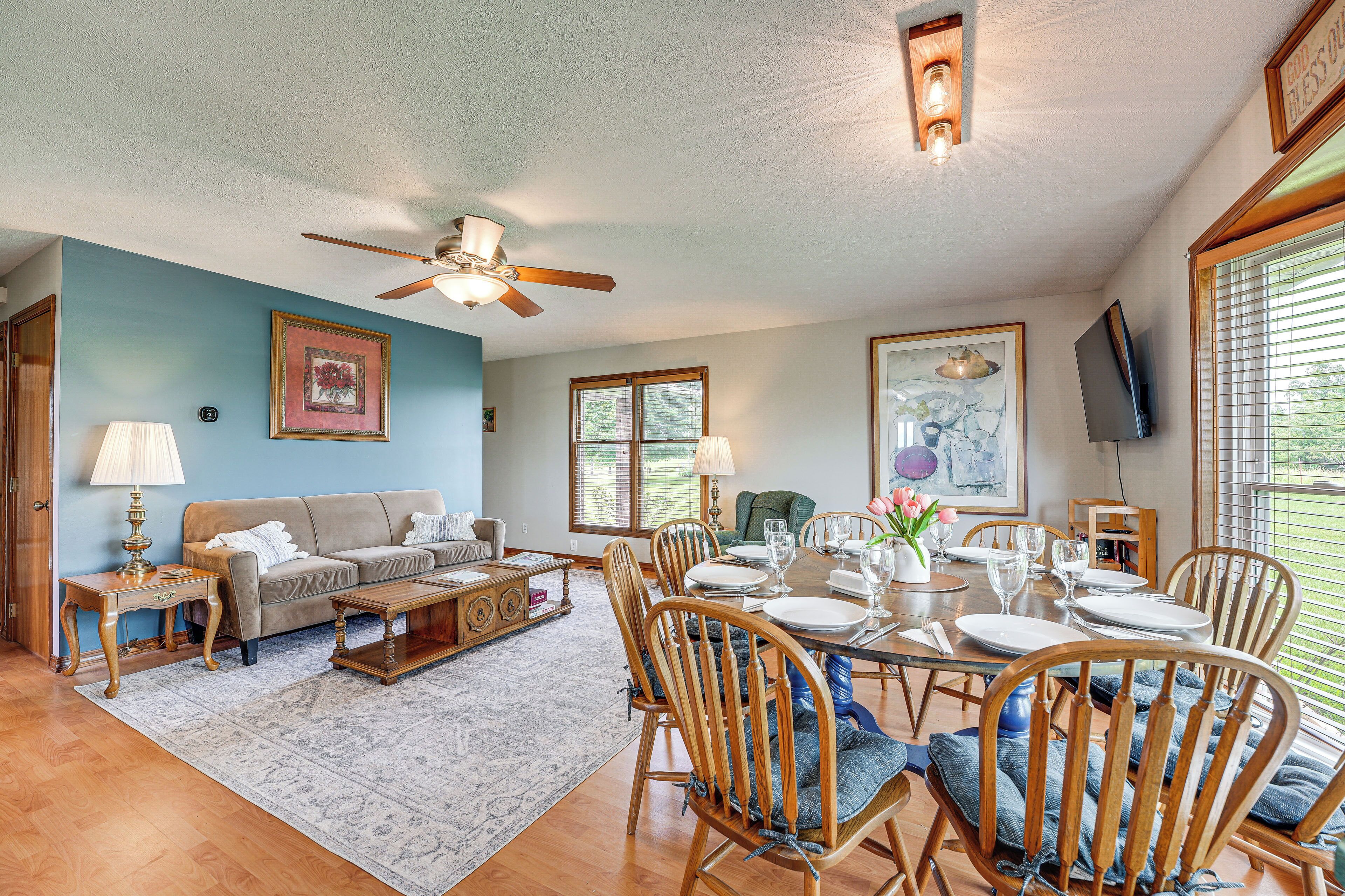 A spacious living room with a sofa, coffee table, and dining table set for six.