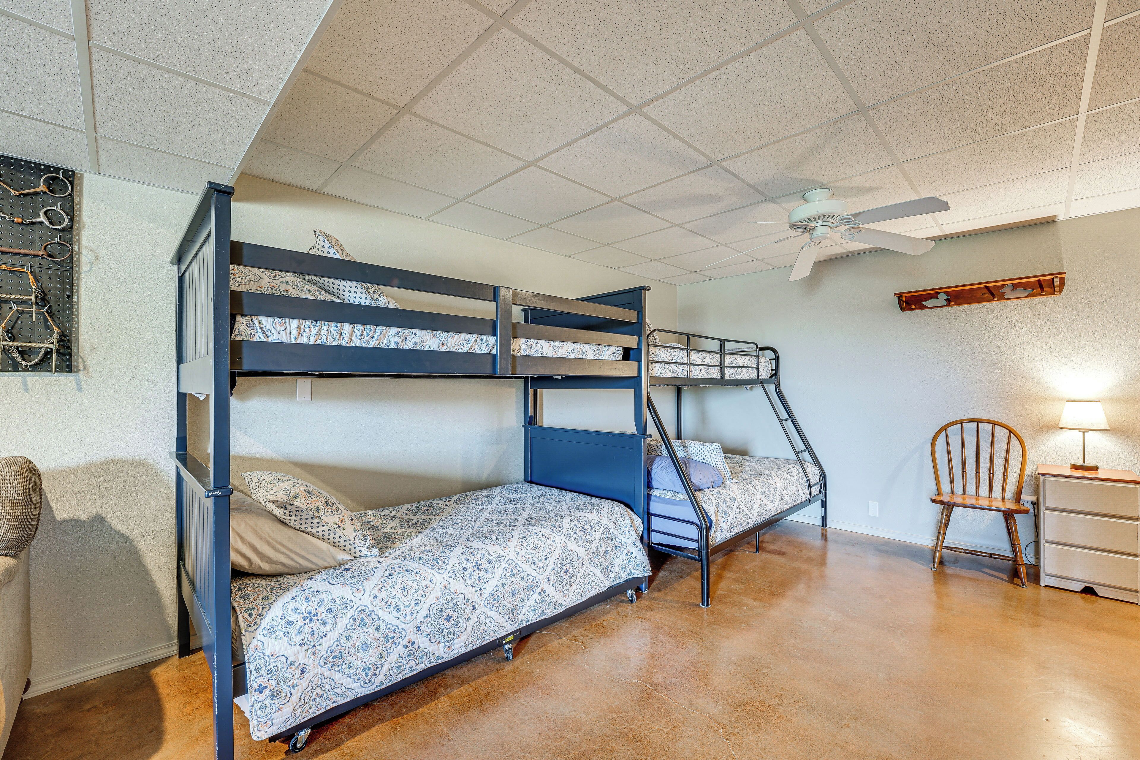 A bunk bed room with a ceiling fan, a chair, and a dresser.