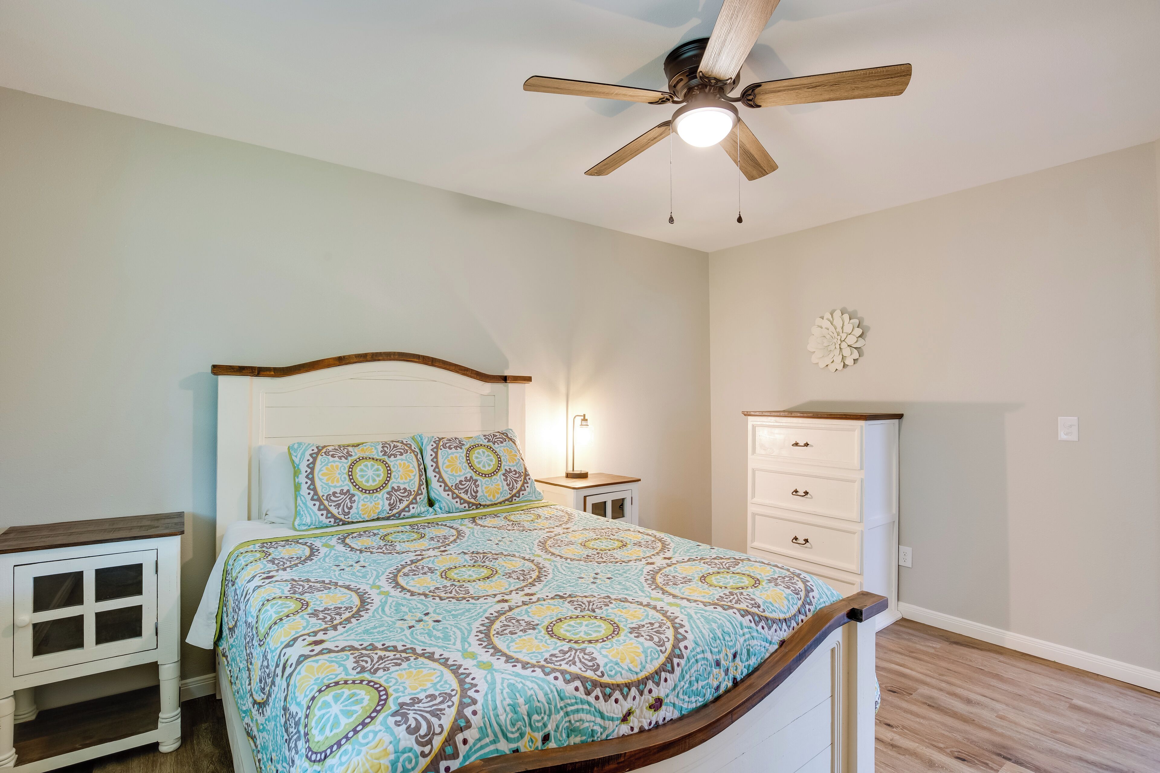 A bedroom with a bed, nightstand, dresser, and ceiling fan.