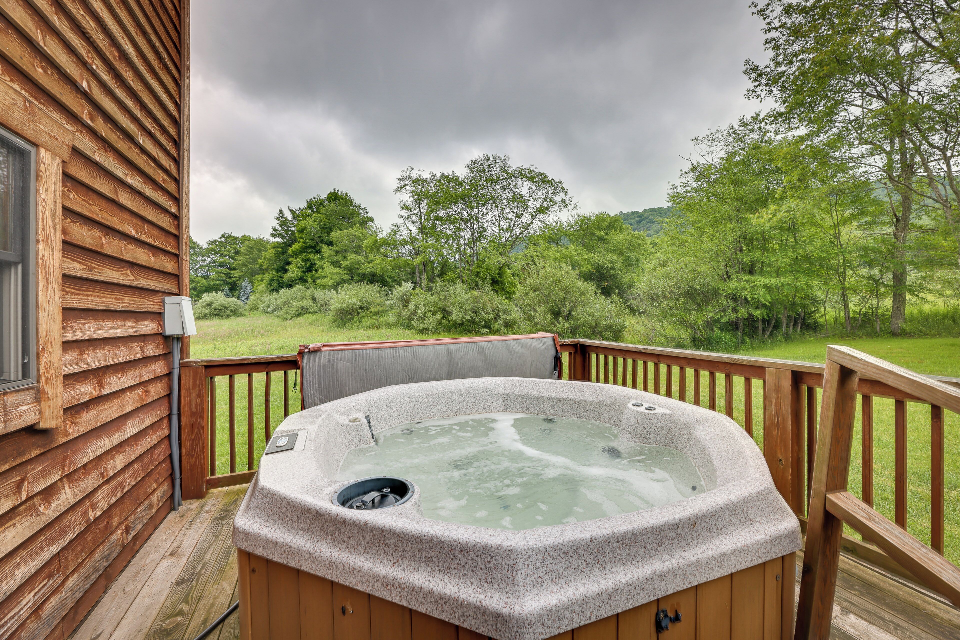 A hot tub on a wooden deck with a view of a forested area.