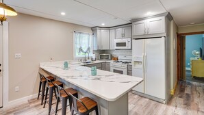 A modern kitchen with a marble island, bar stools, and stainless steel appliances. - Monterey Haven < 1/2 Mi to Lake Garfield w/ Kayaks (Monterey)