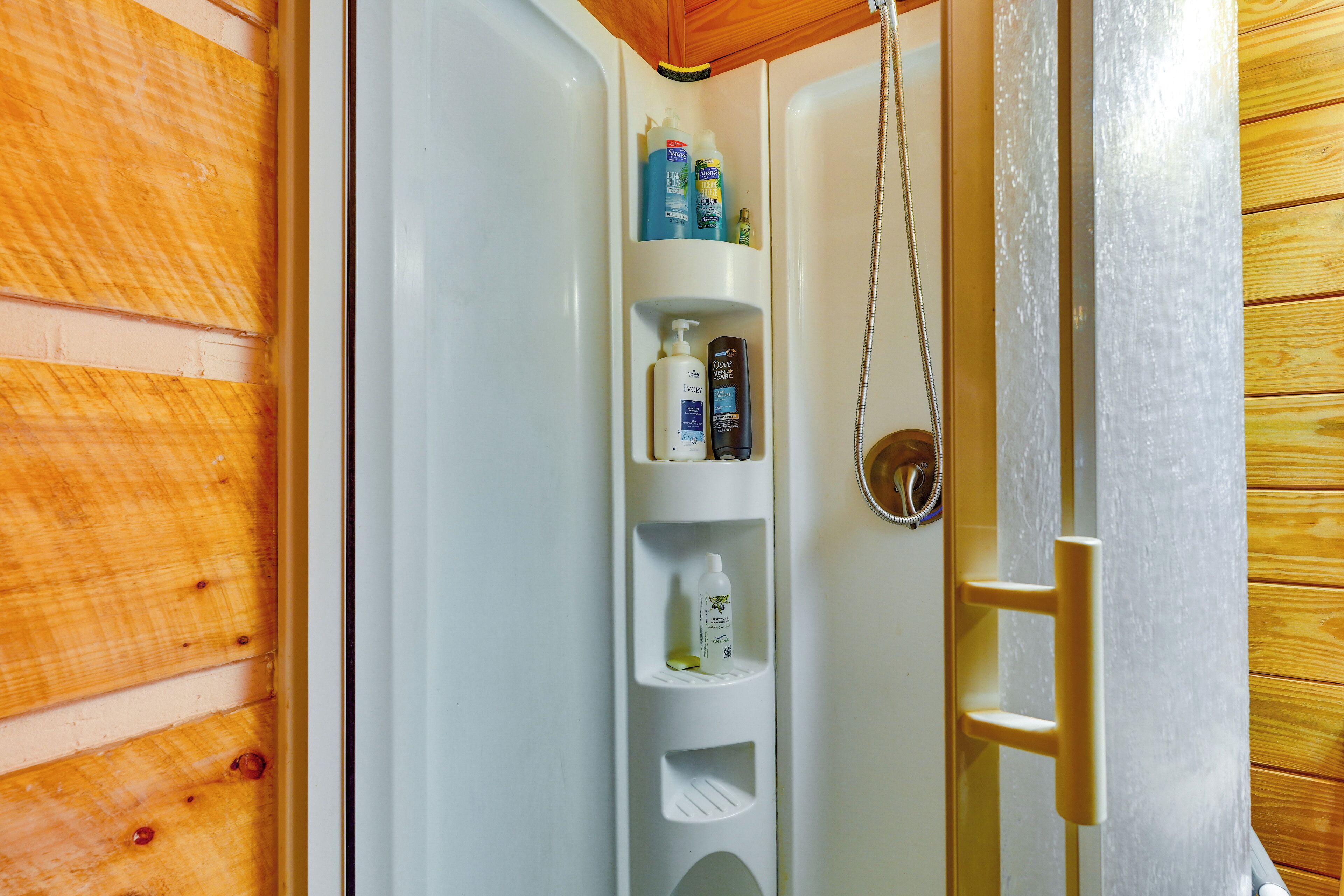 A bathroom with a built-in shelf holding toiletries and a shower area.