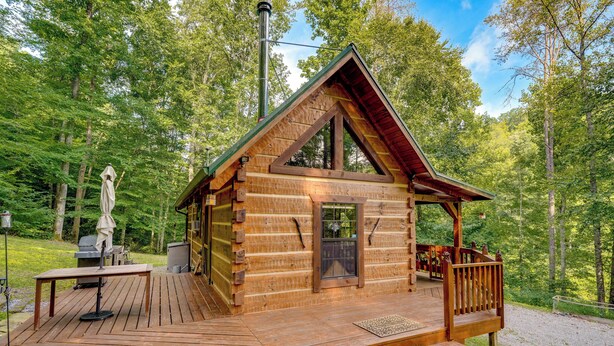 Una cabaña de madera con un porche, un balcón y una chimenea.