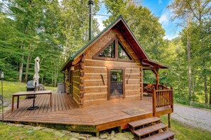 Eine Holzhütte mit einer Terrasse, einer Veranda und einem Schornstein.