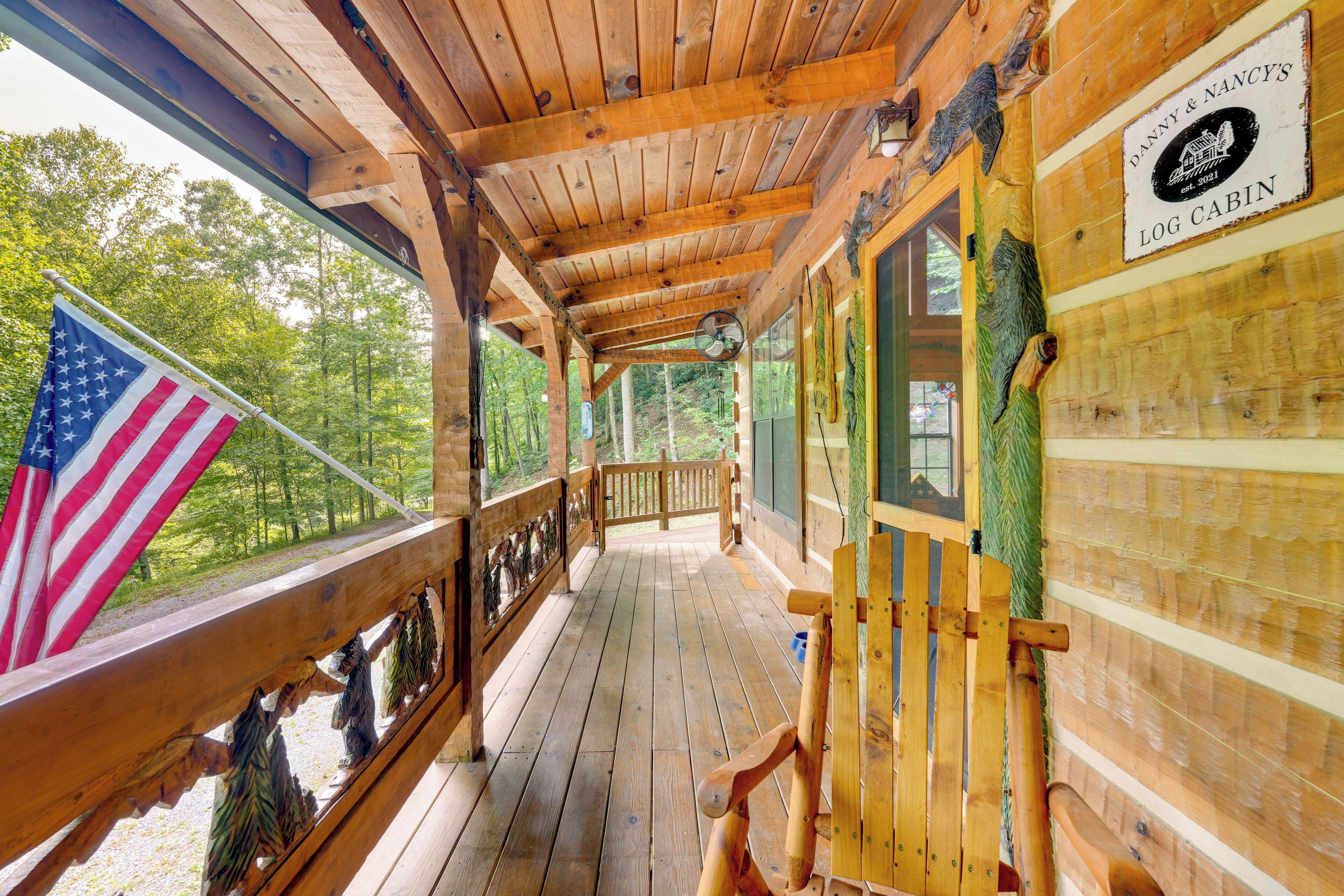 A wooden cabin with a porch, an American flag, and a sign reading "Danny & Nancy's Log Cabin."