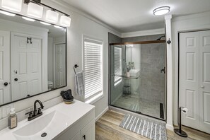 A bathroom with a white sink, a large mirror, and a glass shower enclosure.