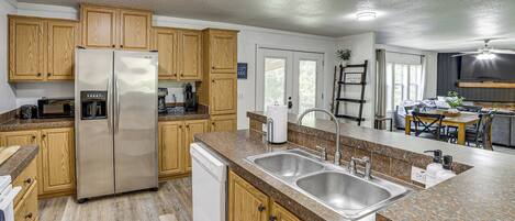 A kitchen with wooden cabinets, stainless steel appliances, granite countertops, and a dishwasher.
