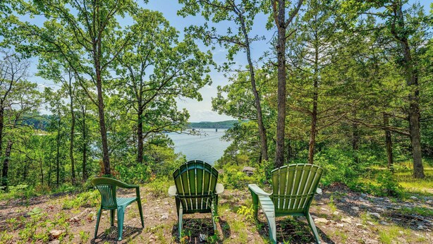 Three green Adirondack chairs facing a lake surrounded by trees. - Fire Pit & Stunning Lake Views: Shell Knob Home! (Shell Knob)