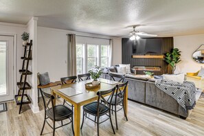 A modern living room with a dining area, a sofa, a TV, and a fireplace.