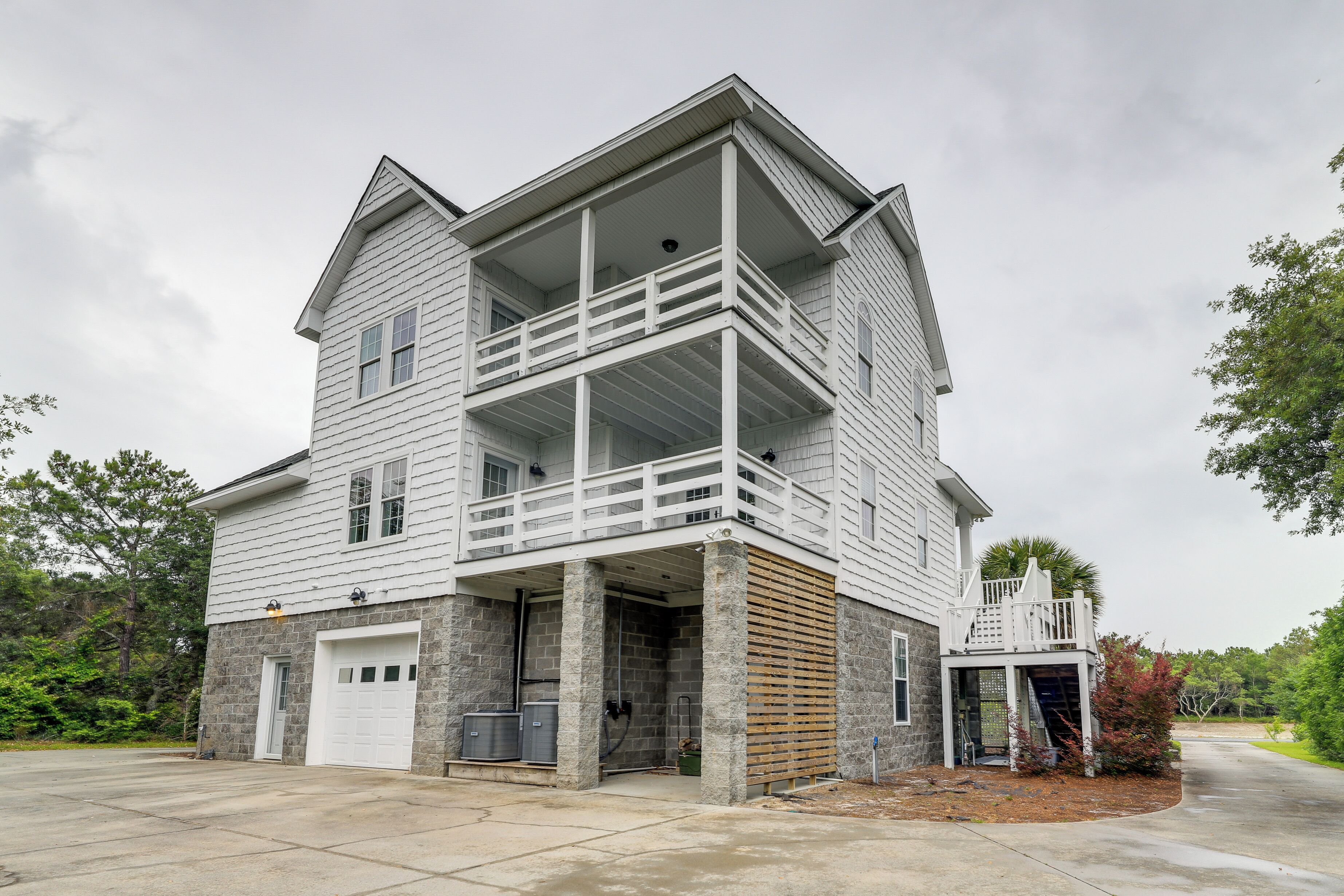 A two-story house with a balcony, a garage, and a stone foundation.