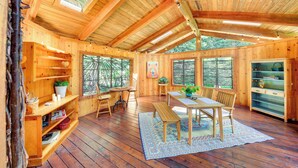 A wooden cabin interior with a dining area, wooden shelves, and large windows. - Unique Nordman Retreat 1 Mi to Priest Lake! (Nordman)