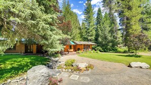 A log cabin with a stone pathway leading to the entrance, surrounded by a well-maintained garden and tall trees. - Unique Nordman Retreat 1 Mi to Priest Lake! (Nordman)