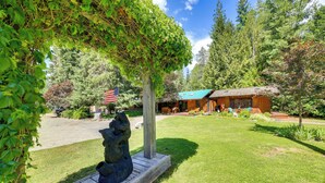 A wooden cabin with a green roof, surrounded by a well-maintained lawn and trees. - Unique Nordman Retreat 1 Mi to Priest Lake! (Nordman)