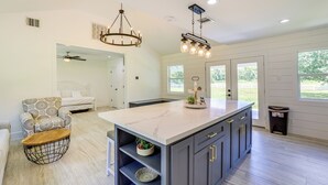 A modern kitchen with a marble island, dark cabinets, and pendant lighting. - Bright Wallis Cottage w/ Pergola & Grill! (Wallis)
