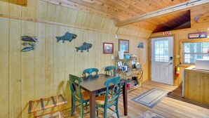 A wooden interior with a dining area, chairs, a table, a kitchen counter, and a door marked "EXIT". - Emory Studio Cabin w/ Lake Fork Boat Access! (Emory)