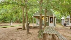 A rustic cabin with a covered porch, a picnic table, and a small outdoor kitchen area surrounded by trees. - Emory Studio Cabin w/ Lake Fork Boat Access! (Emory)