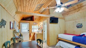 A wooden cabin with a dining area, a kitchenette, a bed, and a ceiling fan. - Emory Studio Cabin w/ Lake Fork Boat Access! (Emory)