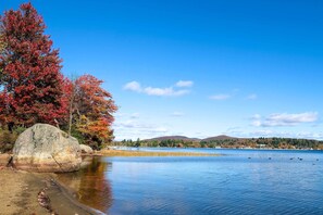 A calm lake with autumn foliage and distant hills. - Beach & Kayaks: Waterfront Cabin on Lake Pleasant! (Speculator)