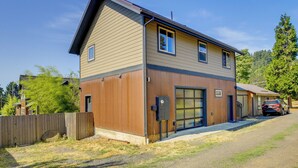 A two-story building with a garage, a wooden fence, and a parked car.