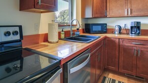 A modern kitchen with wooden cabinets, stainless steel appliances, a microwave, coffee maker, and a dishwasher.