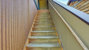 A wooden staircase with a metal railing, leading upwards.