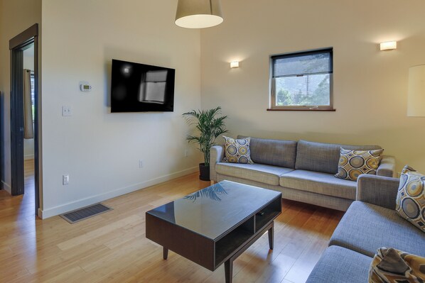 A living room with a sofa, a coffee table, a TV, and a window.