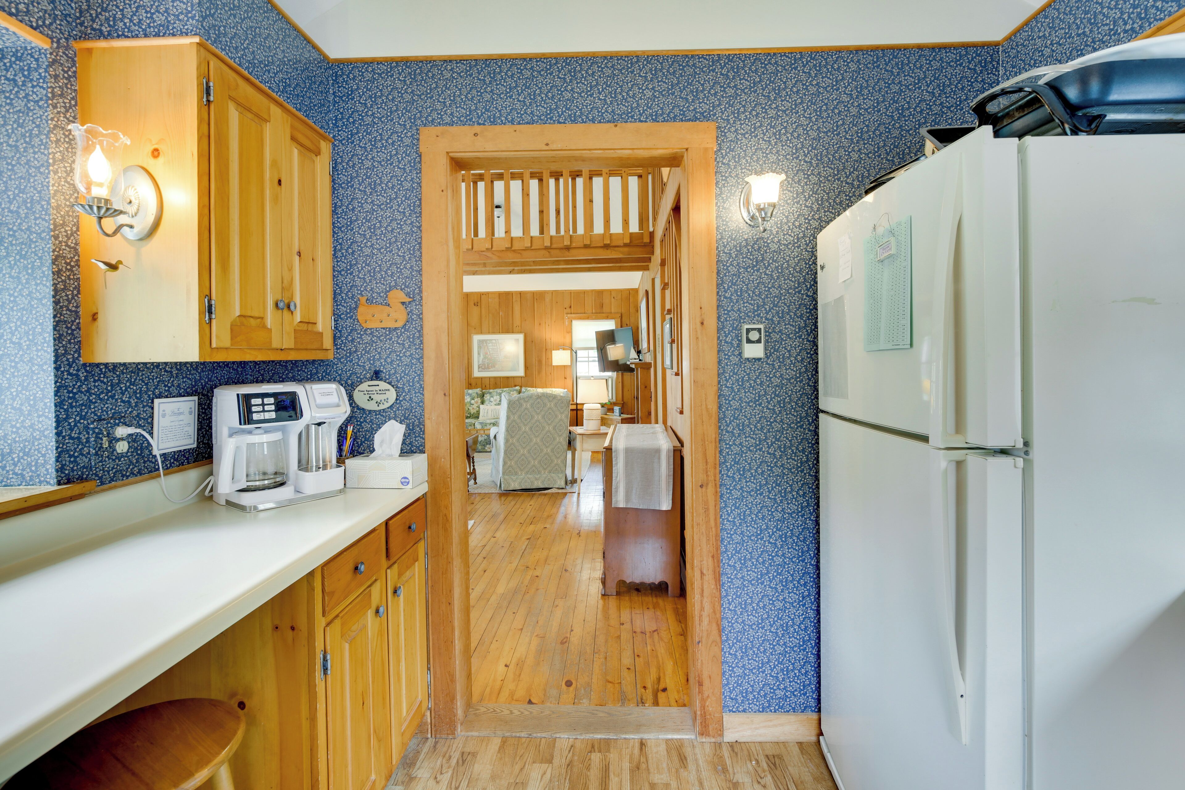 A kitchen with wooden cabinets, a coffee maker, and a refrigerator.