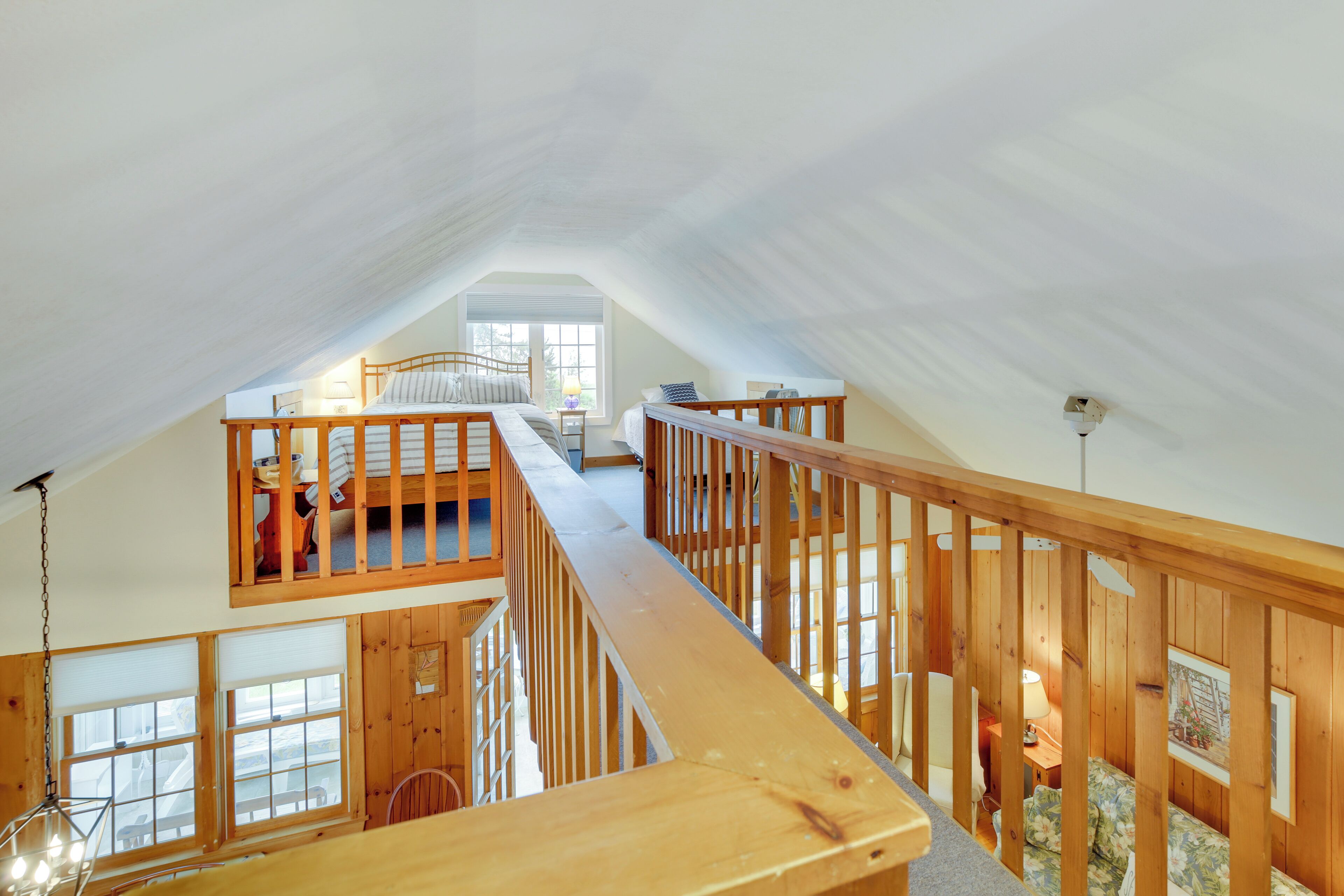 Un dormitorio estilo loft con una escalera de madera, cama, escritorio y ventana.