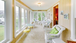 Una habitación soleada con muebles de mimbre, ventanas amplias y techo de madera.