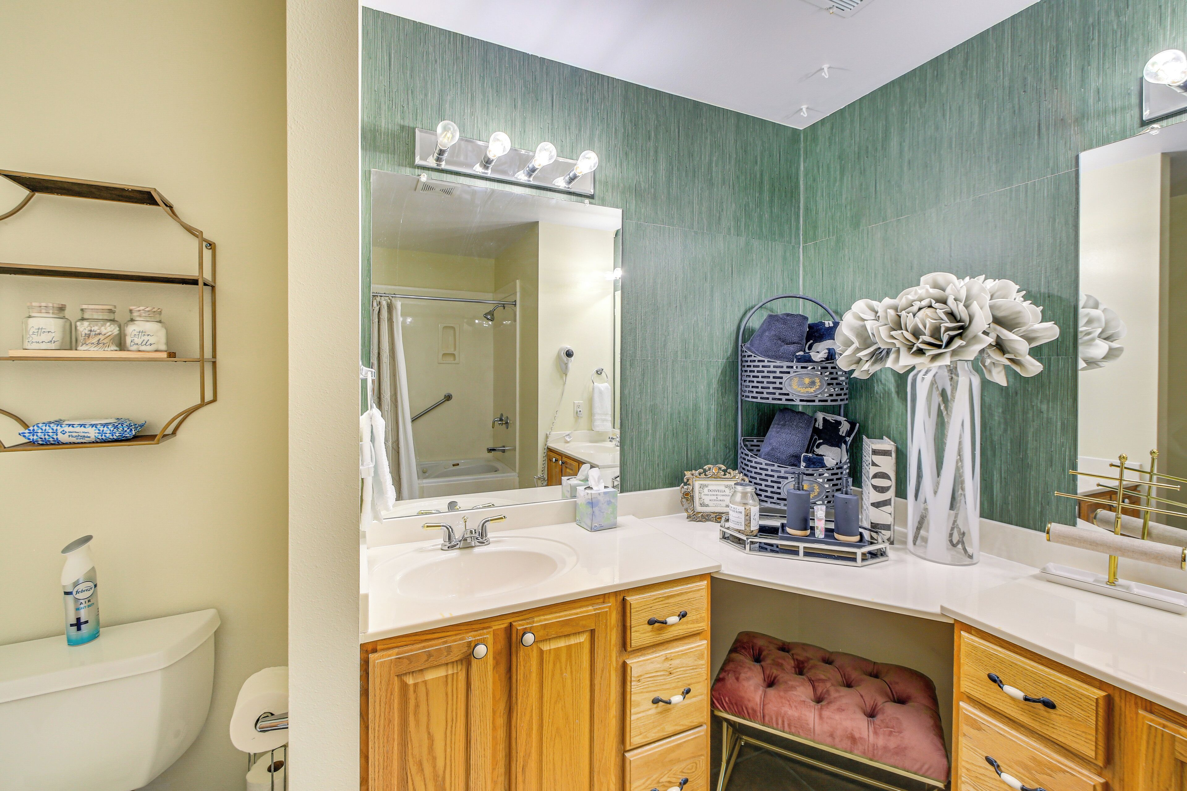 A bathroom with a vanity, sink, mirror, and a vanity with a pink ottoman.