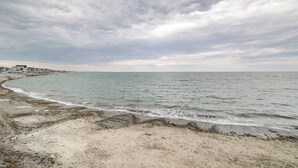 Ein Strand mit sandigem Ufer und ruhiger See unter bewölktem Himmel.