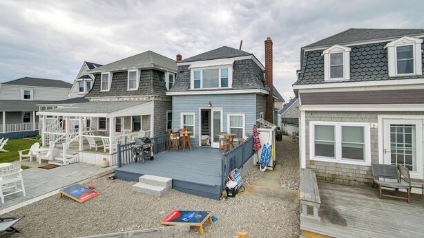 Ein Wohnhaus mit überdachter Terrasse, Sitzgelegenheiten im Freien und einer kleinen Holzterrasse.