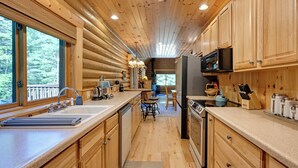 Cocina de cabaña de madera con una ventana grande, un fregadero, una estufa y un refrigerador.