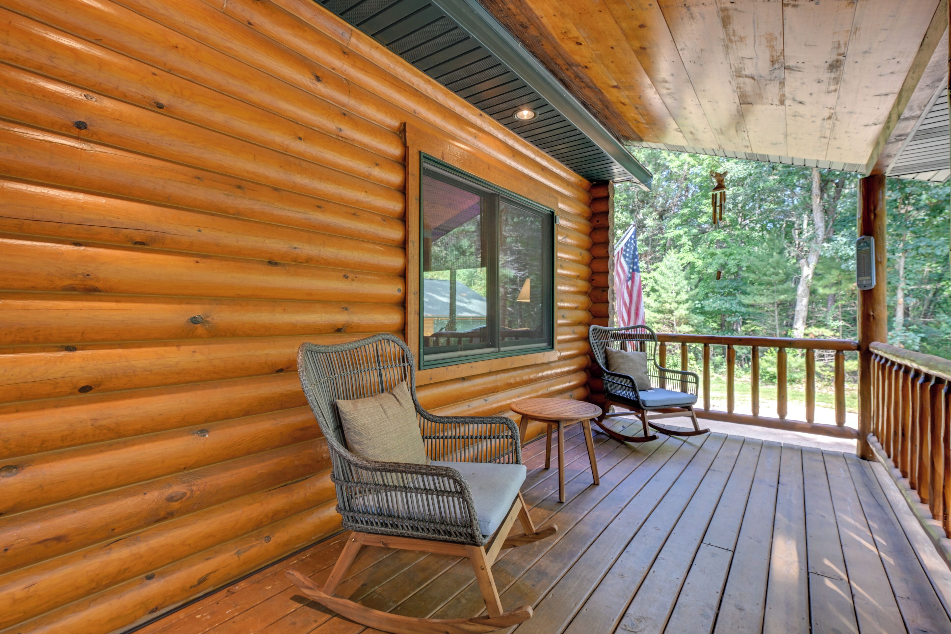 Een houten chalet met een veranda, voorzien van schommelstoelen en een tafel.