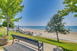 A bench overlooking a beach with a wooden walkway and a clear view of the sea.