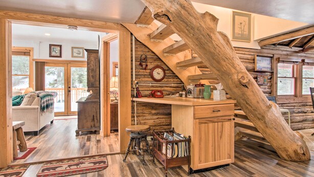 Un intérieur rustique avec un escalier en bois, un coin salon confortable et une bibliothèque.