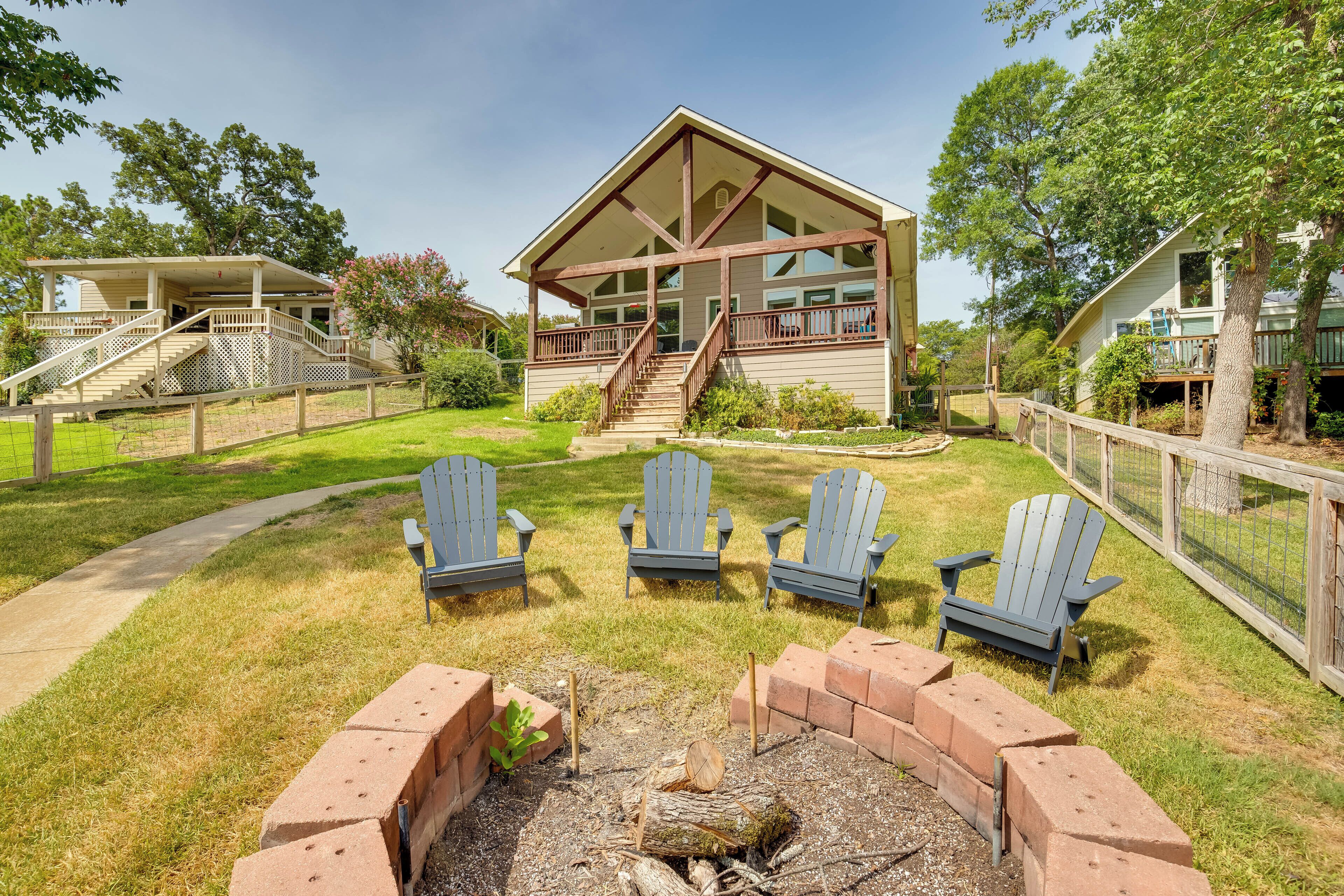 A lodge with a covered porch, a fire pit, and three Adirondack chairs.
