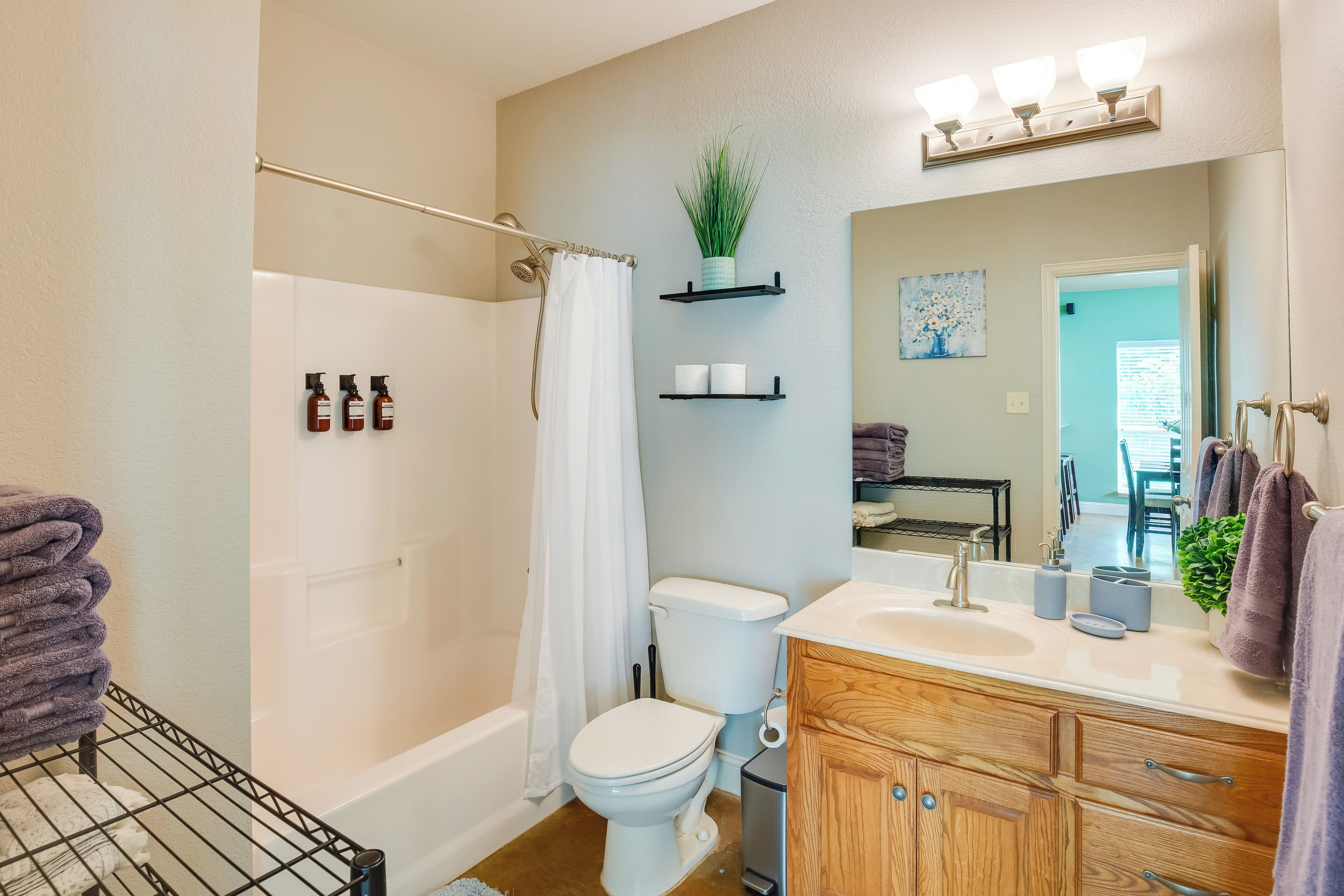 Une salle de bain équipée d’une baignoire, de toilettes, d’un lavabo et d’un meuble-lavabo. On y trouve des serviettes et des articles de toilette sur le comptoir.