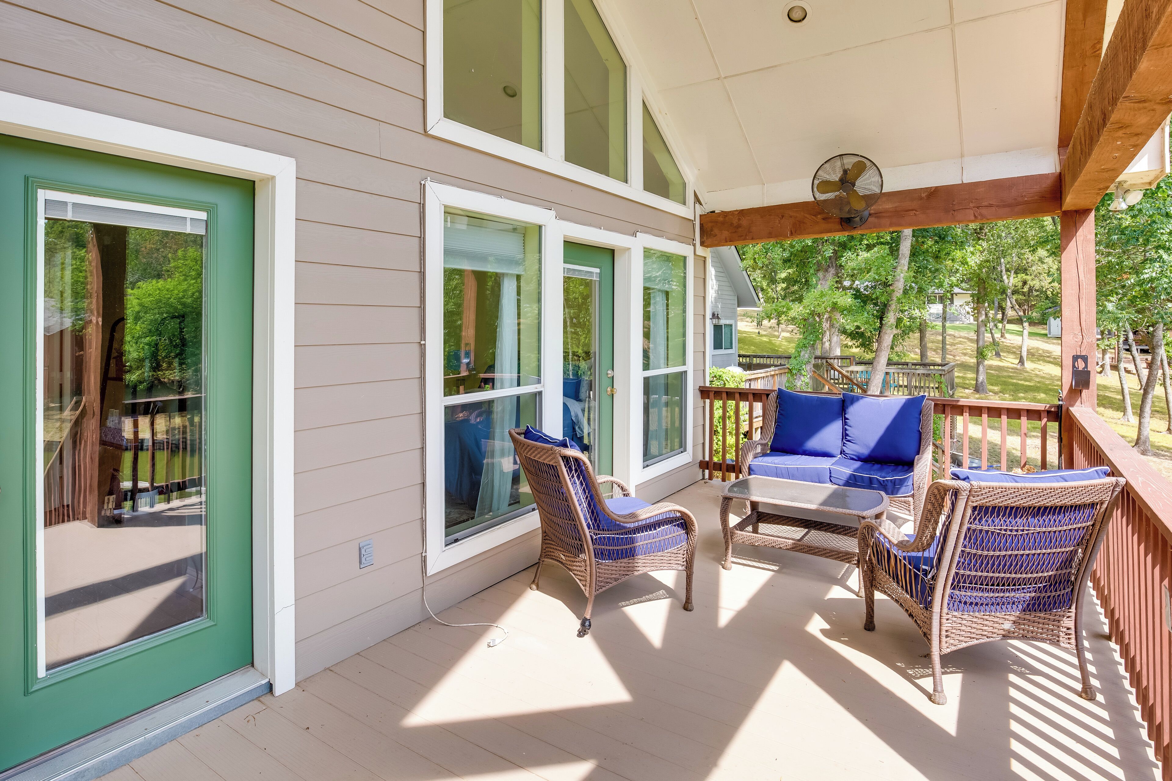 A covered porch with wicker furniture and a fan, large windows, and a view of the yard.