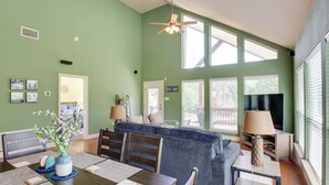 Ein geräumiger Wohnbereich mit Esstisch, blauem Sofa und Deckenventilator.