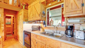A wooden cabin kitchen with a stove, sink, and coffee maker. - Secluded Mountain Cabin w/ Decks + Gazebo! (Warne)