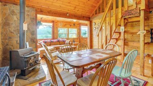 A cabin interior with a stone wall, wooden furniture, a fireplace, and a staircase. - Secluded Mountain Cabin w/ Decks + Gazebo! (Warne)