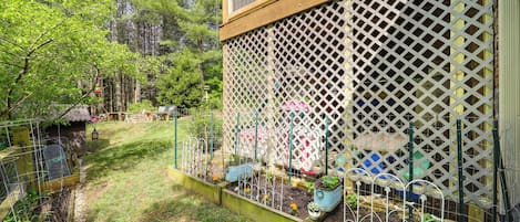Um jardim com canteiros elevados, um deck de madeira e um cercado treliçado.
